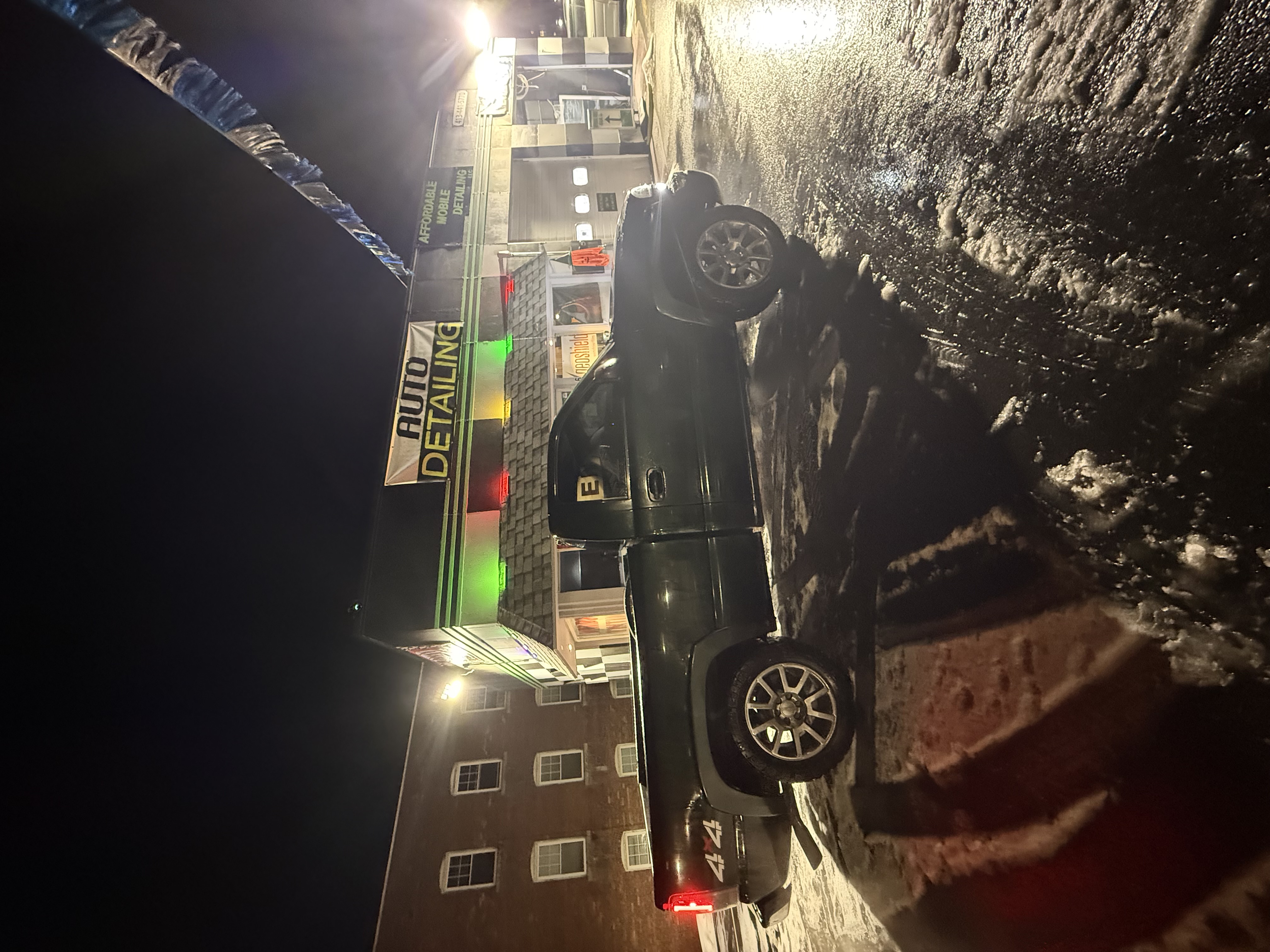 Black pickup truck at night outside auto detailing shop