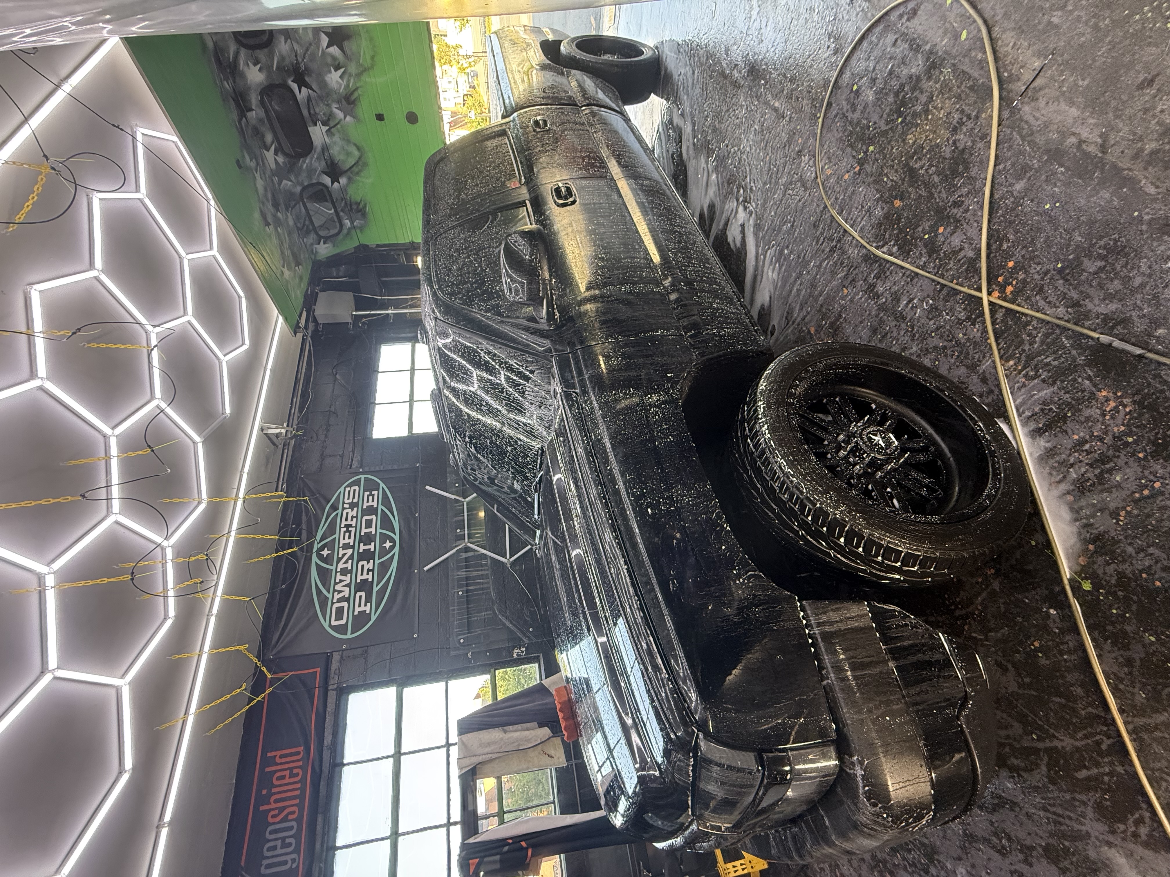 Black pickup truck covered in foam during wash process